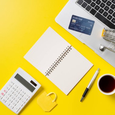 İnternetten alışveriş konsepti. Ofis sarı masa zemininde not, hesap makinesi ve bilgisayar ile kredi kartı satın alma kavramının üst görünümü.