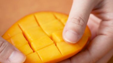 Kadının yavaş çekimde taze mango meyvesi kesmesi ve ev mutfağında yemek için doğranmış hamurun sulu tarafını göstermesi..
