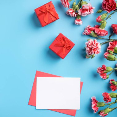 Anneler günü hediyesi. Üst görünüm tasarım tebrik kartı kavramı üzerinde kırmızı karanfil buketi olan parlak mavi masa arkaplanı