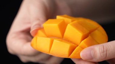 Ağır çekimde kadın taze mango meyvesi kesiyor ve doğranmış posanın sulu tarafını gösteriyor..
