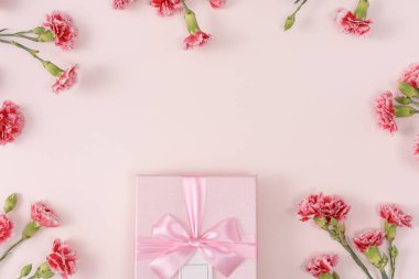 Anneler günü konsepti. Parlak pembe masa arkaplanında karanfil buketli bayram hediyesi tasarımı