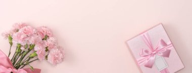 Anneler günü konsepti. Parlak pembe masa arkaplanında karanfil buketli bayram hediyesi tasarımı