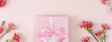 Anneler günü konsepti. Parlak pembe masa arkaplanında karanfil buketli bayram hediyesi tasarımı