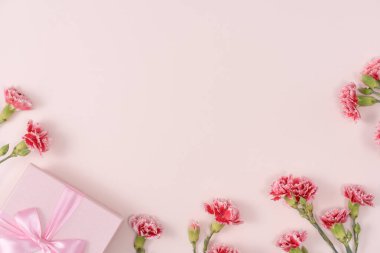 Anneler günü konsepti. Parlak pembe masa arkaplanında karanfil buketli bayram hediyesi tasarımı
