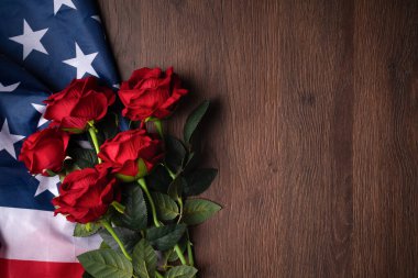 ABD kavramı. Bağımsızlık Günü ya da Anma Günü. Ulusal bayrak ve kırmızı gül koyu ahşap masa zemininde.