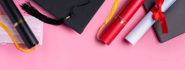 Mezuniyet karesi akademik şapkası diploması ve maskesi pembe masa arkasında izole..