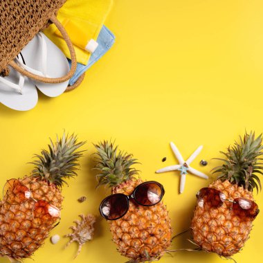 Yaz meyvesi tasarımı konsepti. Deniz kabukları, ananas ve sarı arka planda palmiye yaprakları olan tatil gezilerinin en iyi manzarası..