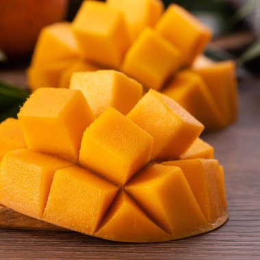 Mango. Taze olgun mango meyvelerini koyu ahşap masa zemininde yeşil yapraklarla kaplayın..