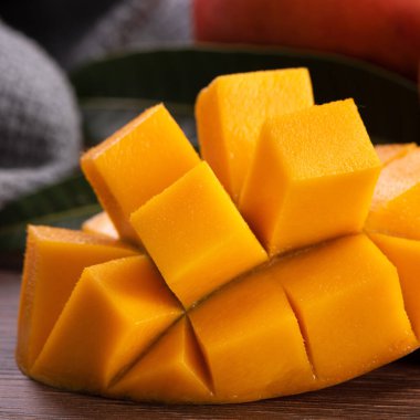 Mango. Taze olgun mango meyvelerini koyu ahşap masa zemininde yeşil yapraklarla kaplayın..