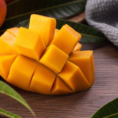 Mango. Taze olgun mango meyvelerini koyu ahşap masa zemininde yeşil yapraklarla kaplayın..