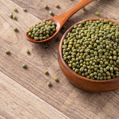 Ahşap masa arkasındaki bir kasedeki çiğ fasulyeyi kapat..