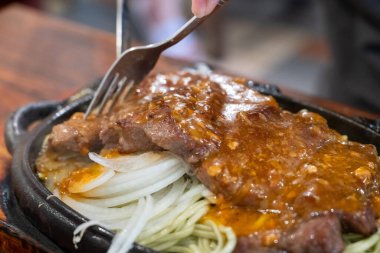 Tayvan usulü sıcak biftek, erişte, yumurta ve sos ve sıcak demir tabakta..