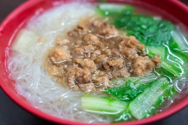 Bir kase Tayvan pirinçli şehriye kıymalı ve sebzeli kırmızı kasede lezzetli bir et suyu..