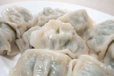 Taze, lezzetli sarımsaklı soğanlı börek, yeşil soğanlı ciaozi, ahşap masa arkasında beyaz tabakta.