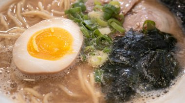 Rich tonkotsu ramen with char siu, soft-boiled egg, and seaweed in a savory broth.