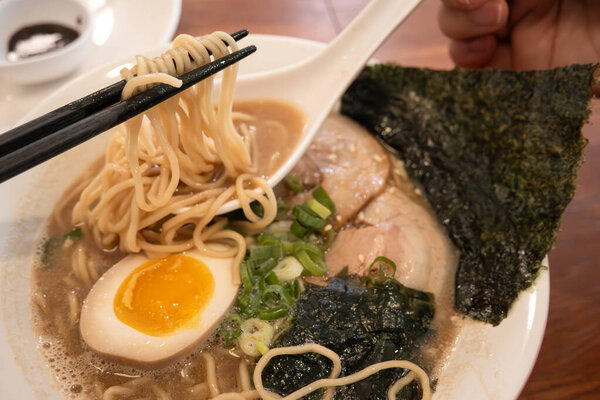 Rich tonkotsu ramen with char siu, soft-boiled egg, and seaweed in a savory broth.