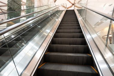 Aşağıdan görülen temiz metal yürüyen merdiven modern bir iç mekanda tekrarlanan adımları gösteriyor..