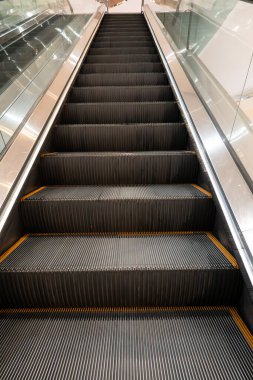 Aşağıdan görülen temiz metal yürüyen merdiven modern bir iç mekanda tekrarlanan adımları gösteriyor..