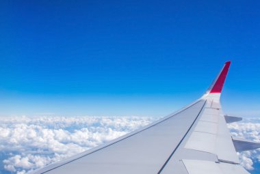 Olarak görülen bir uçak pencereden mavi gökyüzü ve bulutlar