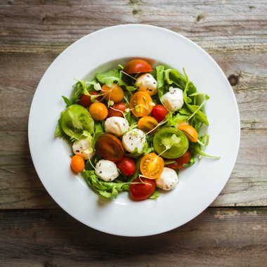 Roka, domates ve mozarella ahşap arka plan üzerinde salatası