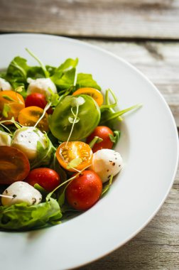 Roka, domates ve mozarella ahşap arka plan üzerinde salatası