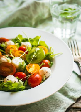 Roka, domates ve mozarella ahşap arka plan üzerinde salatası