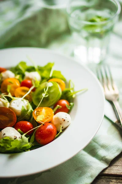 Salade avec roquette, tomates et mozarella sur fond bois — Photo