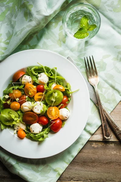 Ensalada con rúcula, tomates y mozarella sobre fondo de madera —  Fotos de Stock