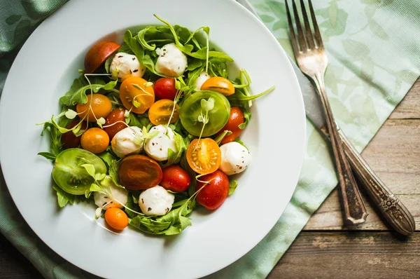 Ensalada con rúcula, tomates y mozarella sobre fondo de madera —  Fotos de Stock