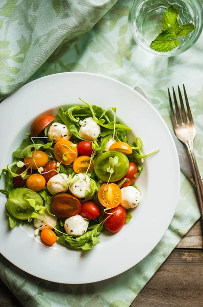 Ensalada con rúcula, tomates y mozarella sobre fondo de madera —  Fotos de Stock