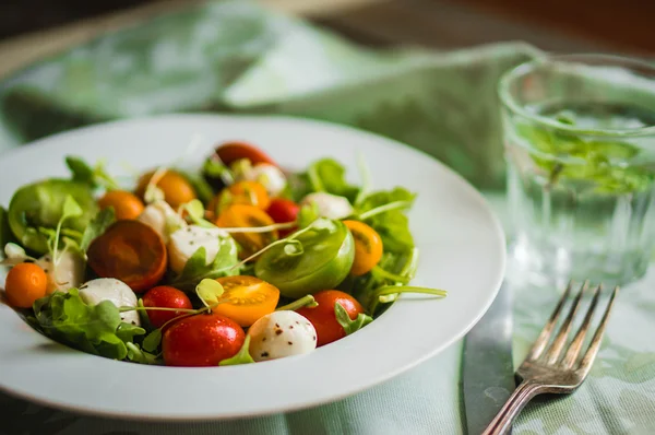 Salade avec roquette, tomates et mozarella sur fond bois — Photo