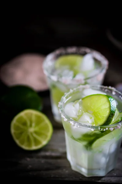 Wasser mit Eis und Limetten auf rustikalem Hintergrund — Stockfoto