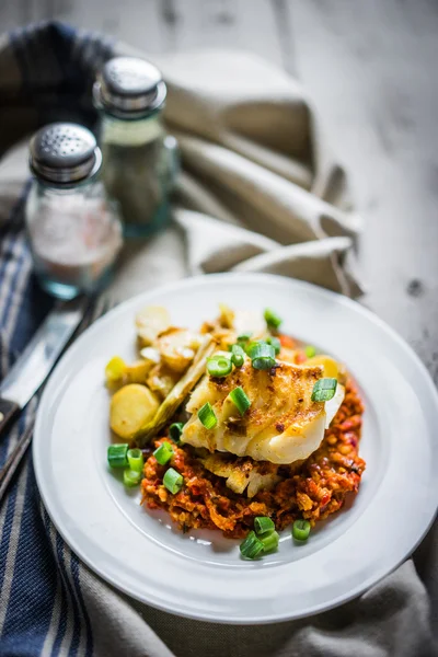 Roasted hake with romesco sauce and onion on wooden background — Stock Photo, Image