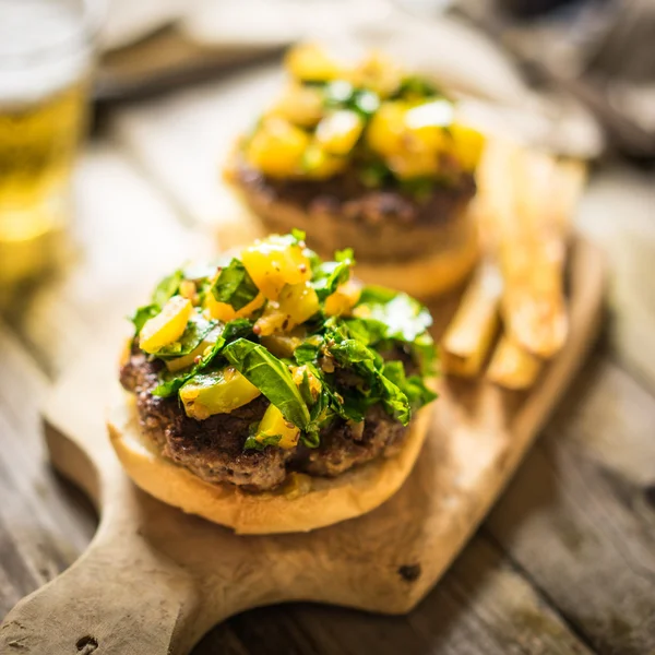 Hambúrgueres caseiros com batatas fritas em fundo de madeira — Fotografia de Stock
