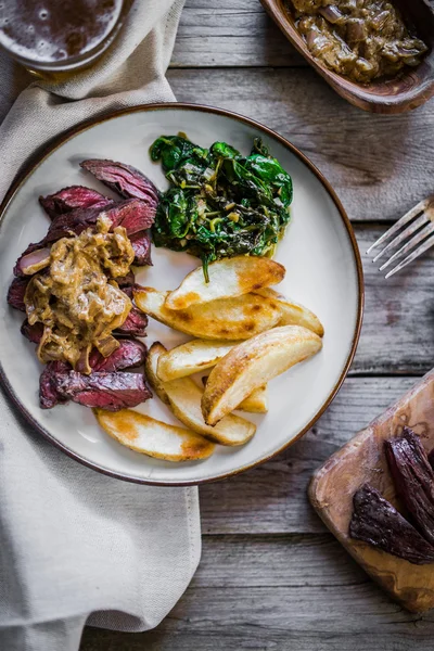 Steak with baked botatoes and green salad on wooden background — Stock Photo, Image