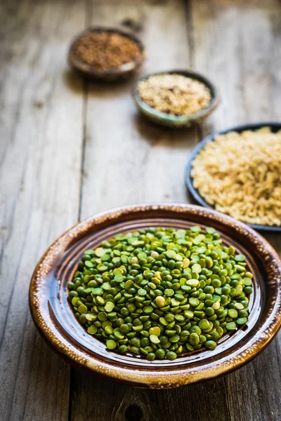 Ervilhas, arroz integral, quinoa e trigo sarraceno sobre fundo de madeira — Fotografia de Stock