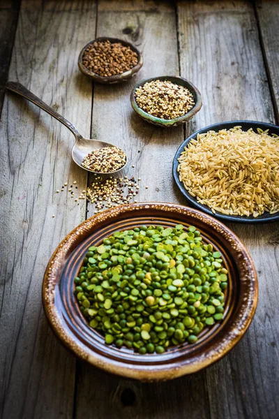 Ervilhas, arroz integral, quinoa e trigo sarraceno sobre fundo de madeira — Fotografia de Stock