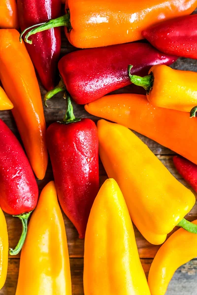 Kleurrijke paprika's op rustieke achtergrond — Stockfoto