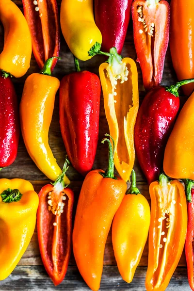 Kleurrijke paprika's op rustieke achtergrond — Stockfoto