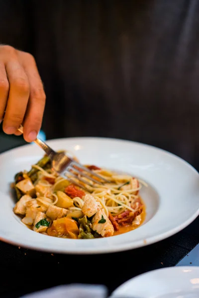 Man is eating pasta with chicken and vegetables — Stock Photo, Image