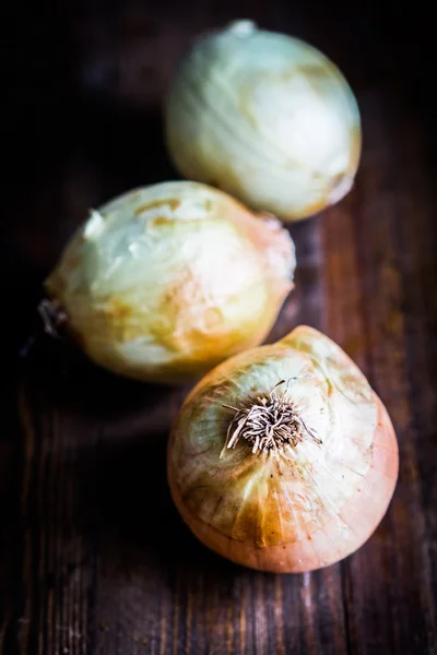 Yellow onions on wooden background — Stock Photo, Image