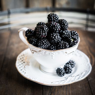 Böğürtlen ahşap arka plan üzerinde bir kupa