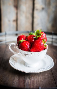 Ahşap arka plan üzerine bir fincan taze çilek