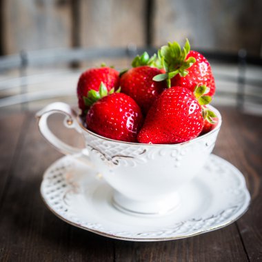 Ahşap arka plan üzerine bir fincan taze çilek