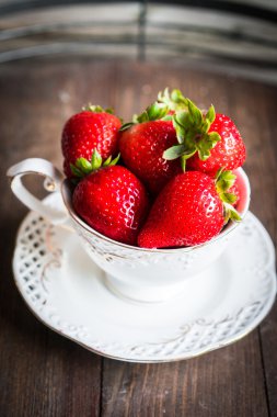 Ahşap arka plan üzerine bir fincan taze çilek