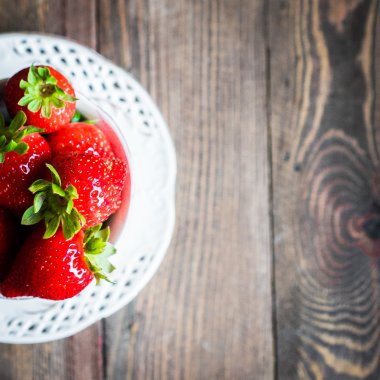 Ahşap arka plan üzerine bir fincan taze çilek