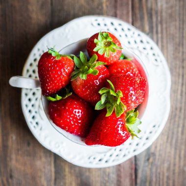 Ahşap arka plan üzerine bir fincan taze çilek