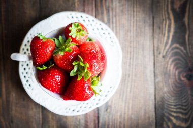 Ahşap arka plan üzerine bir fincan taze çilek