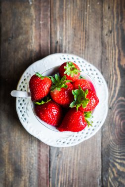 Ahşap arka plan üzerine bir fincan taze çilek