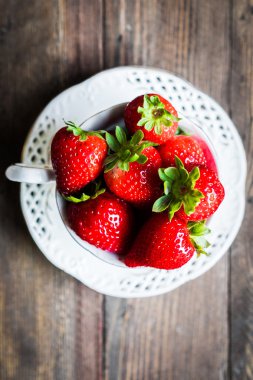 Ahşap arka plan üzerine bir fincan taze çilek